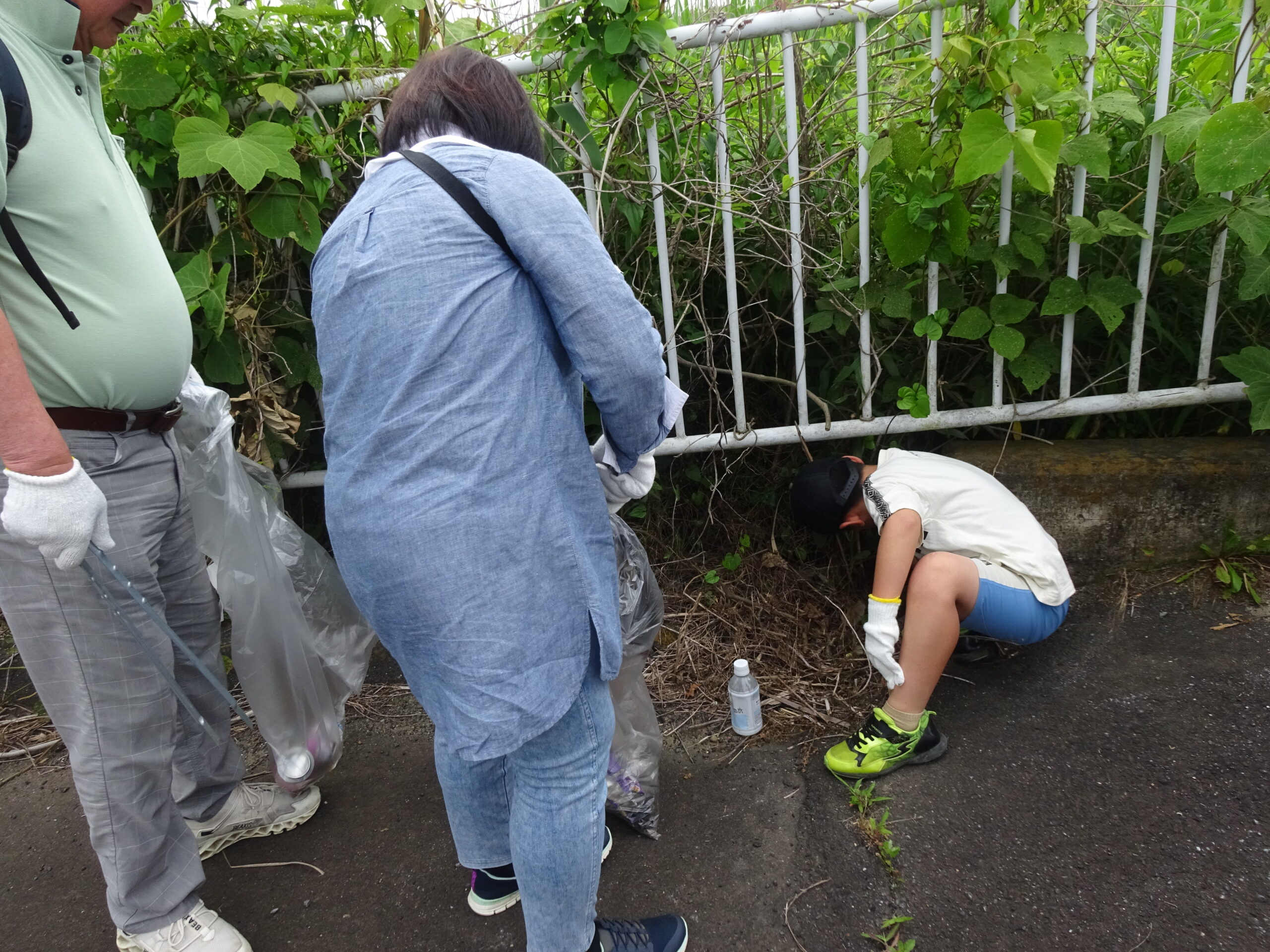 子どもが草むらからゴミを見つけて疲労様子